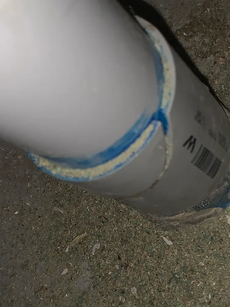 Close up of a cracked 40mm basin waste socket causing water leaks under a vanity cabinet.