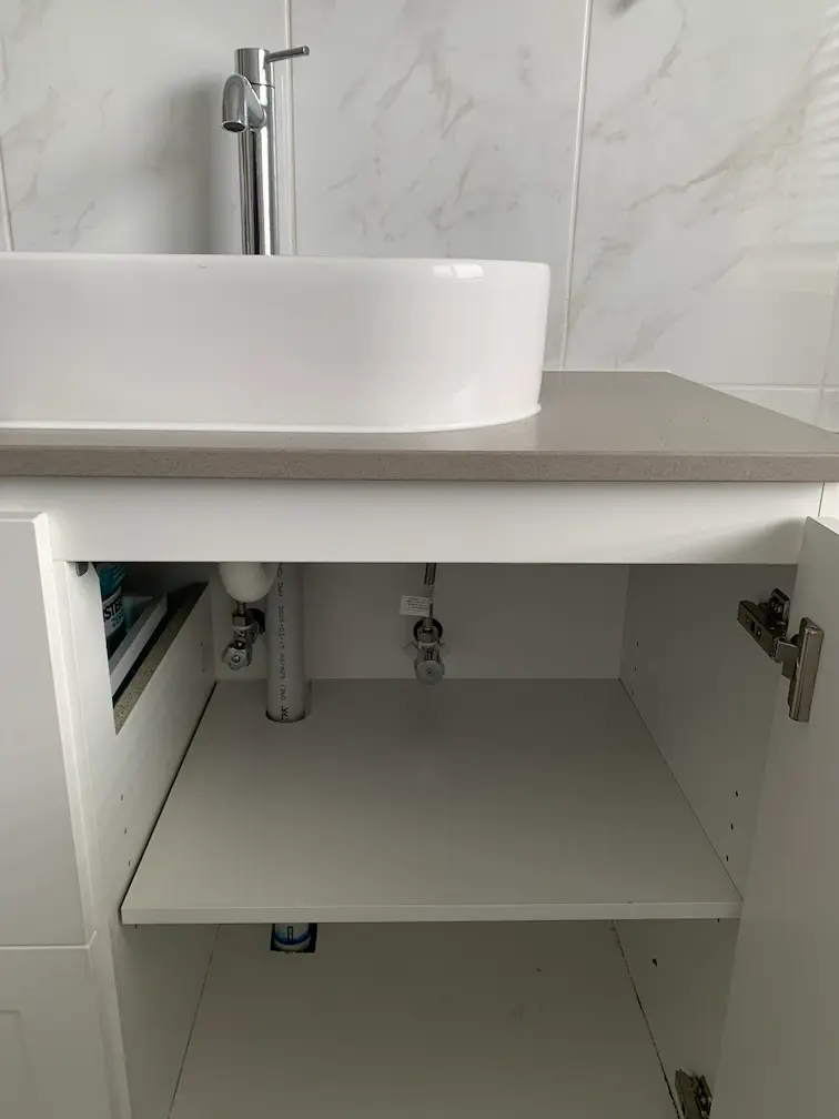 Final repair of bathroom vanity plumbing with new pipework and clean access cover installation.